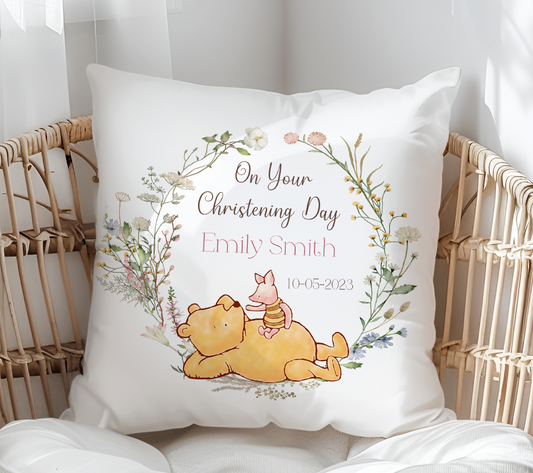Decorative pillow with Winnie the Pooh and Piglet design, text 'On Your Christening Day Emily Smith', on a wicker chair.