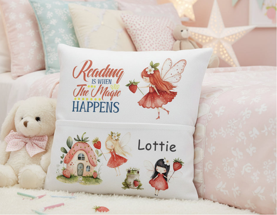 A personalized white throw pillow with whimsical fairy and cottage illustrations, featuring the text 'Reading is when The Magic HAPPENS' and the name 'Lottie', styled on a bed in a soft pink bedroom setting.