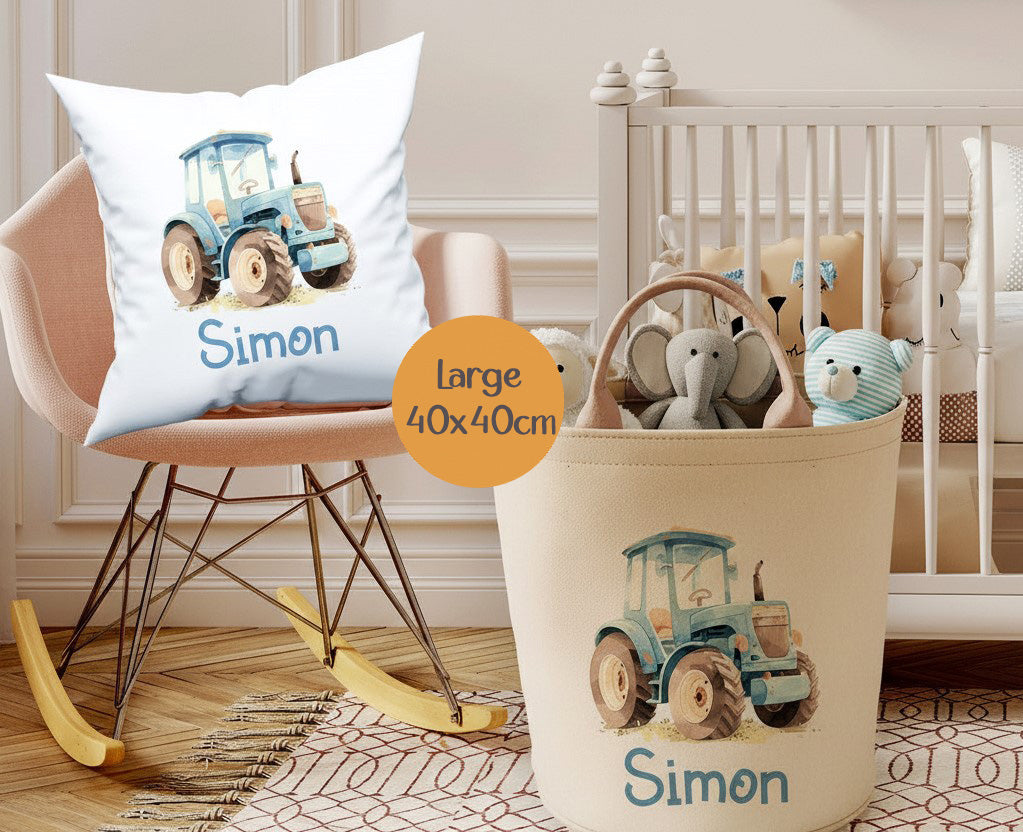Personalized nursery decor set featuring a white throw pillow and a beige fabric storage bin, both printed with a blue tractor illustration and the name 'Simon'. The scene is styled in a nursery with a rocking chair, crib, and toys.