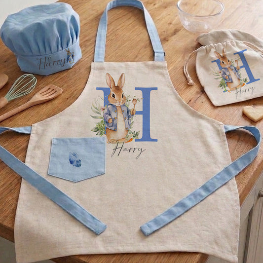 Personalized Peter Rabbit children's apron and chef hat set in blue and white gingham with custom name embroidery and adjustable straps.