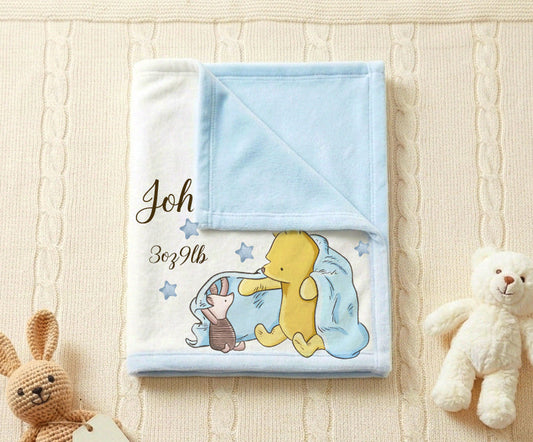 A folded baby blanket with a light blue reverse side and a printed cartoon illustration of Winnie the Pooh hugging a blue bunny, placed on a cream cable-knit blanket with a plush teddy bear and a small stuffed rabbit prop.