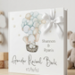 A personalized hardcover gender reveal book with a white bow, featuring an illustration of a baby elephant in a hot air balloon and the text 'Shannon & Ryan's Gender Reveal Book' on a light wood shelf.