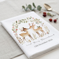 A folded white waffle-weave tea towel with a personalized woodland deer illustration and the text 'and Mrs Blanchard 13th December 2026', styled on a light linen surface with a spoon, eucalyptus sprig, and small red berries.