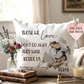 Decorative pillow with a bulldog illustration and text, placed on a table with books and a candle.