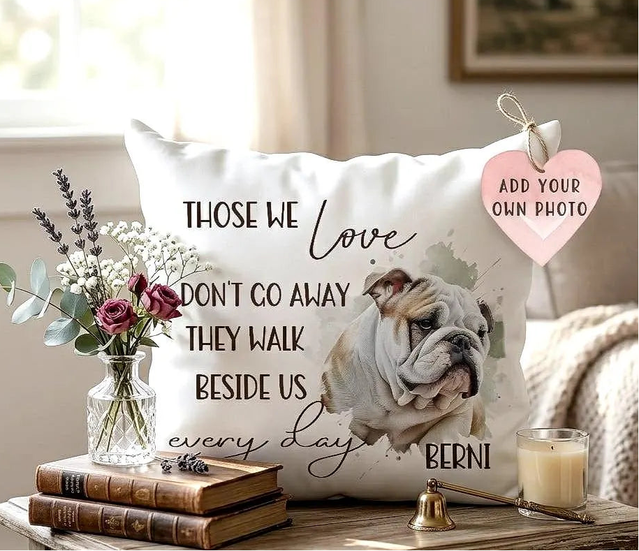 Decorative pillow with a bulldog illustration and text, placed on a table with books and a candle.