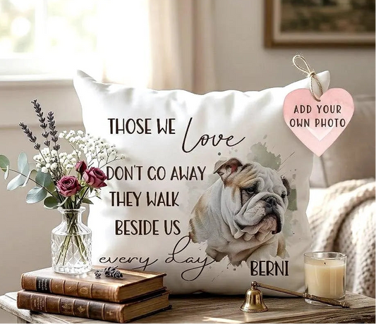 Decorative pillow with a bulldog illustration and text, placed on a table with books and a candle.