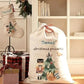 A personalized cream-colored Christmas Santa sack with 'Thomas' and 'Christmas presents' printed on it, styled in a cozy holiday room next to a matching hanging stocking.